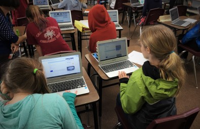 Students Sitting At Desks Using Chromebooks In Classrooms